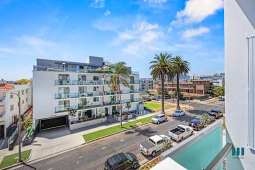 A modern apartment building with a parking lot in front.