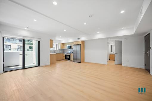 A spacious kitchen with wooden floors and white walls.