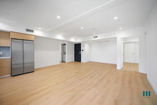 A spacious room with wooden flooring and white walls.