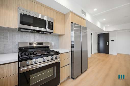 A kitchen with a stove, microwave, and refrigerator.