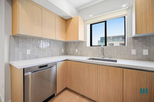 A kitchen with wooden cabinets and a stainless steel dishwasher.