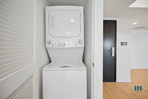 A white washing machine in a room with a wooden floor.