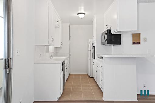 A kitchen with white cabinets and appliances.