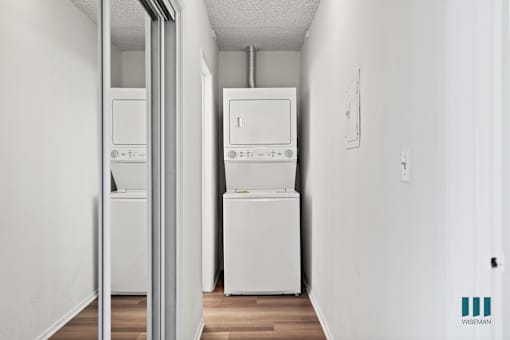 A white wall with a fridge and a washing machine.