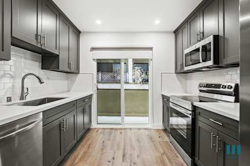 A modern kitchen with dark wood cabinets and stainless steel appliances.