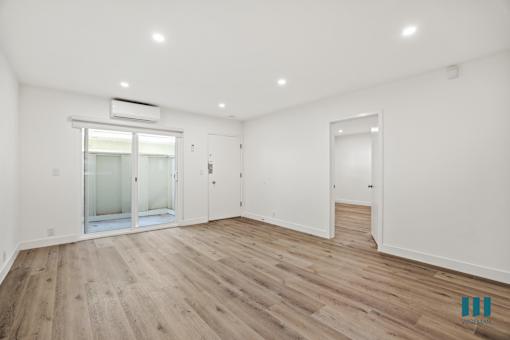 A spacious room with wooden flooring and white walls.