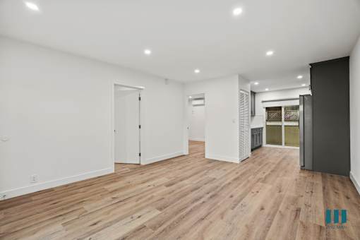 A spacious room with wooden flooring and white walls.
