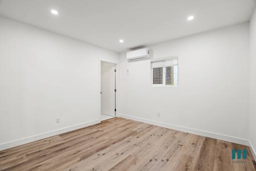 A room with wooden flooring and a window with blinds.