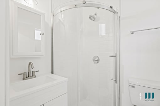 A white bathroom with a sink, shower, and toilet.