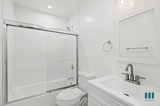 A white bathroom with a toilet, sink, and shower.