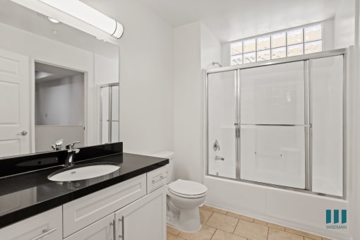 Bathroom with Full-Size Bathtub with Glass Door and Vanity Cabinet with Storage