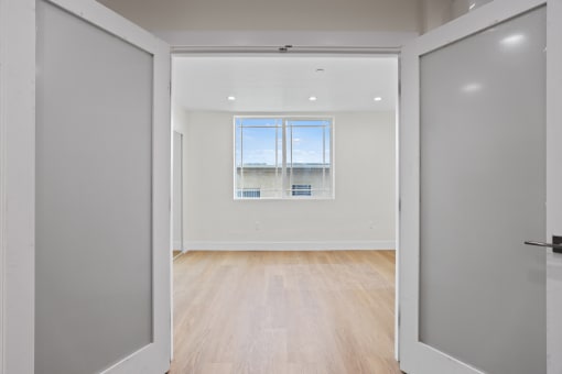 Double-Doors Leading to Bedroom Space with Window, Recessed Lighting, and Vinyl Flooring