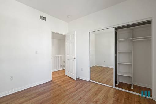 a bedroom with a closet and a hard wood floor
