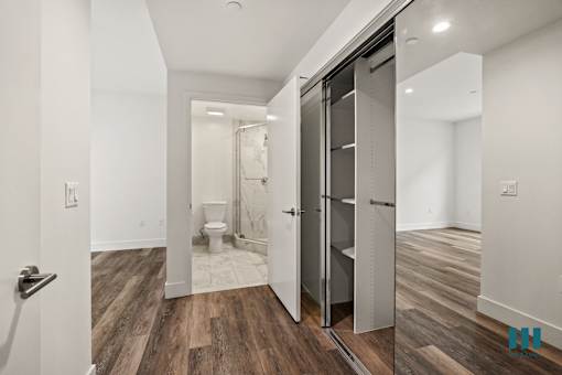 Bedroom with Large-Size Mirrored Closet with Built-In Shelving and Bathroom