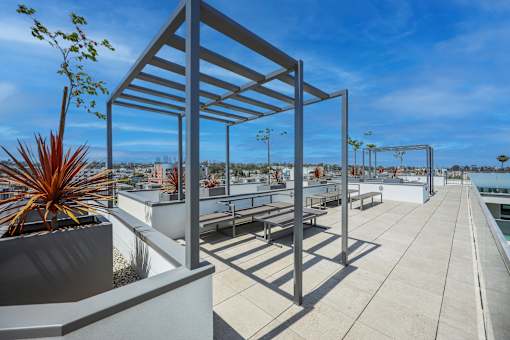 A modern outdoor seating area with a metal pergola and concrete planters.
