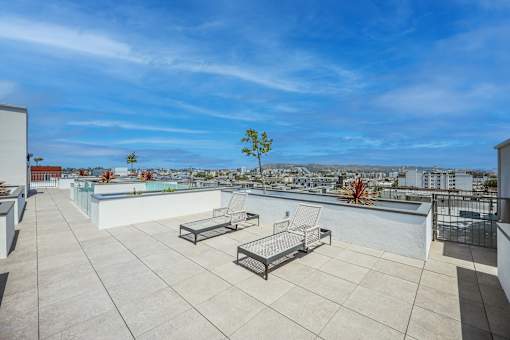 A rooftop patio with a table and chairs overlooking a cityscape.