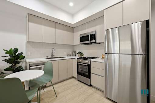A modern kitchen with a stainless steel refrigerator, a microwave above the oven, and a sink with a faucet.