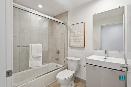 A white towel hangs on a glass shower door.