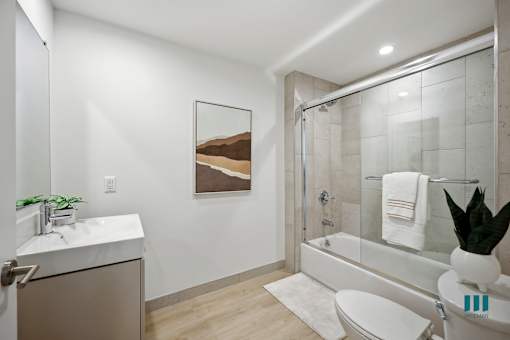 A bathroom with a white toilet, sink, and a painting of a mountain scene on the wall.