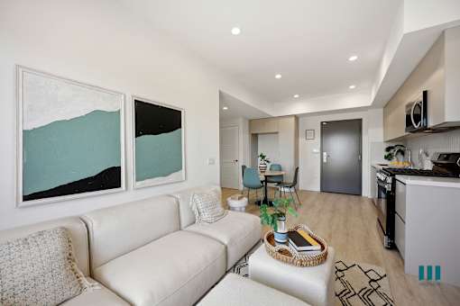 A modern living room with a white couch and a painting on the wall.