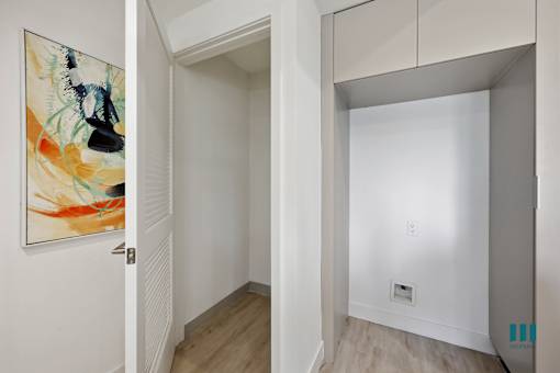 A hallway with a painting on the wall and a white door.