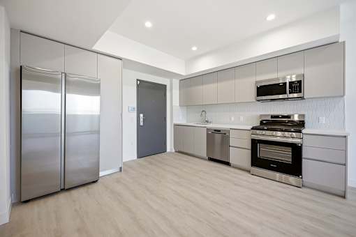 A modern kitchen with a stainless steel refrigerator and oven.