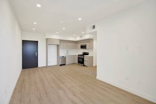 A spacious room with a kitchen area and a refrigerator.