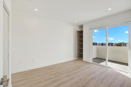 A room with a sliding glass door leading to a balcony.