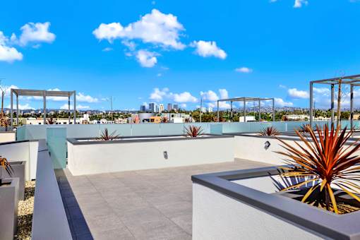 A rooftop patio with a concrete floor and white walls.