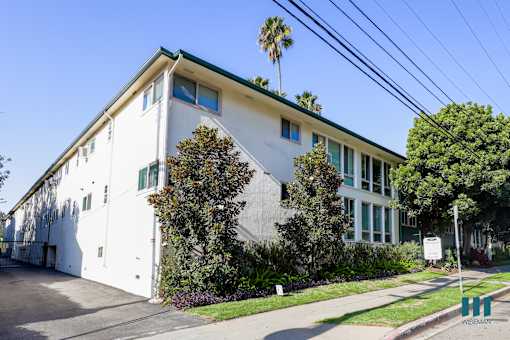 A white building with a green roof and a tree in front of it.