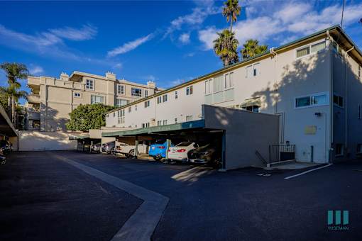 A parking lot in front of a building with a palm tree in the background.