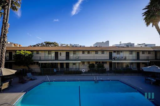 A swimming pool in front of a building with a clear blue sky.