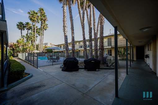 A patio with a pool and palm trees in the background.