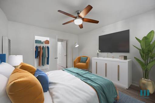 A bedroom with a bed, a chair, a cabinet, a plant, and a ceiling fan.