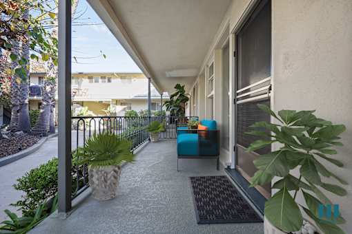 A patio with a blue couch and a pineapple planter.