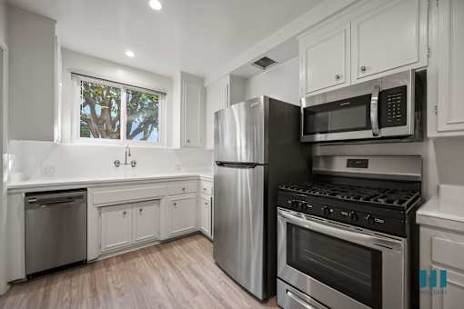 A modern kitchen with stainless steel appliances and white cabinetry.