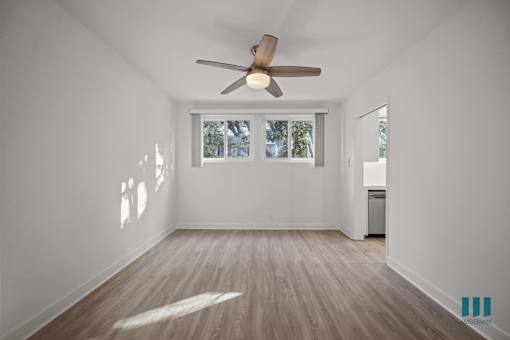 A room with a ceiling fan and a window with blinds.