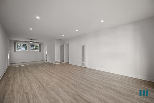 A spacious room with wooden flooring and white walls.