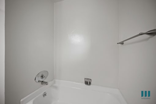 A white bathroom with a bathtub and a shower head.