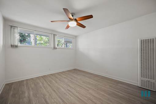 A room with a ceiling fan and wooden flooring.