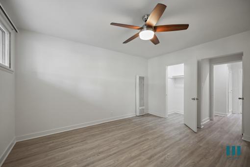 A room with a ceiling fan and wooden flooring.