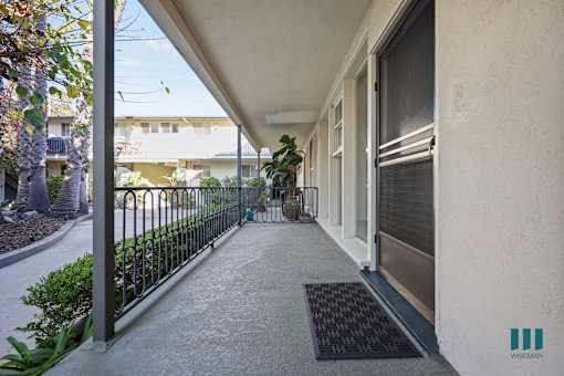 A black mat is on the concrete walkway of a building.