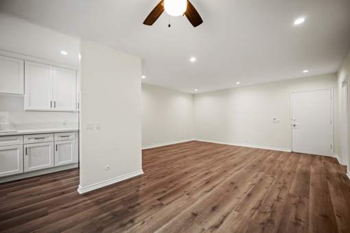a living room with white walls and a ceiling fan