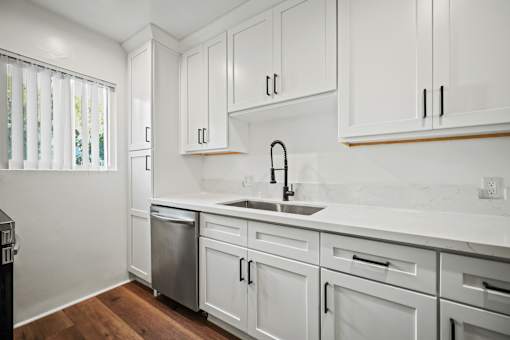 a kitchen with white cabinets and a sink and a window