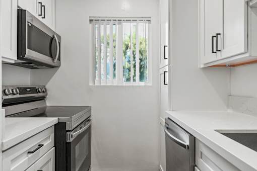 a kitchen with white cabinets and stainless steel appliances and a window