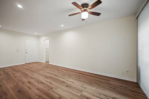 an empty living room with white walls and a ceiling fan
