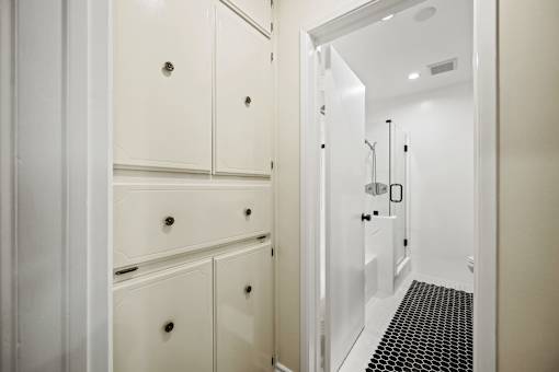 a white hallway with white cabinets and a door to a bathroom