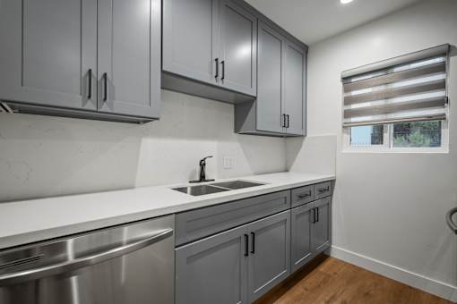 an empty kitchen with gray cabinets and stainless steel appliances