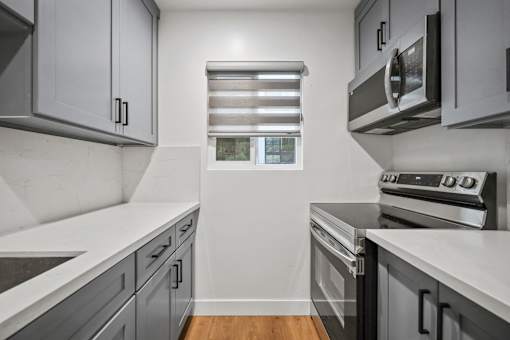 an empty kitchen with white counter tops and stainless steel appliances