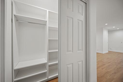 a walk in closet with white shelves and a white door